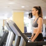 Een vrouw die traint op een opvouwbare loopband in haar woonkamer voor thuisfitness.