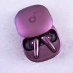 Een persoon die geniet van muziek met noise cancelling oordopjes in een drukke trein, omringd door storende geluiden.
